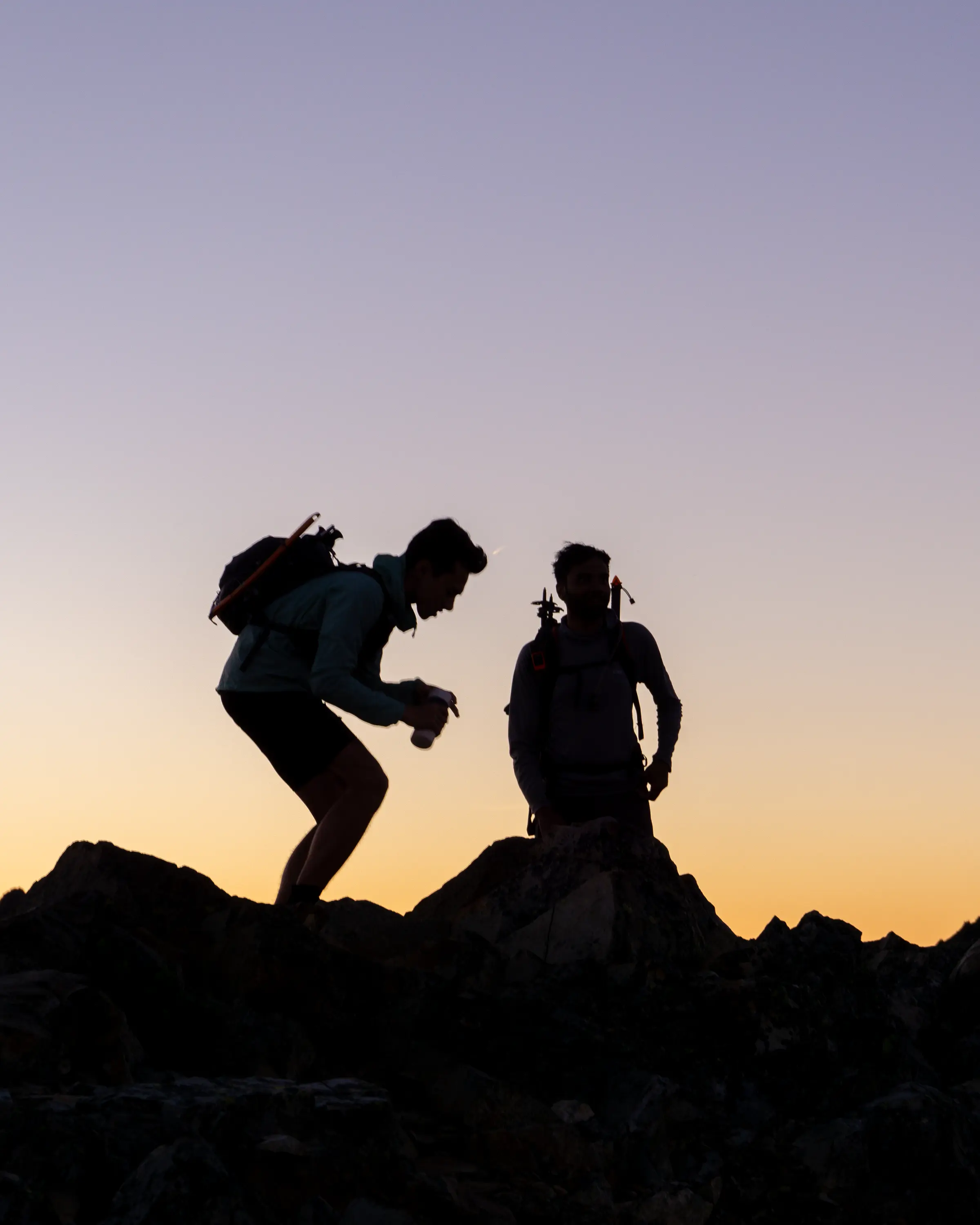 A friend reaches down to open the summit register during an evening scramble near Snoqualmie Pass.