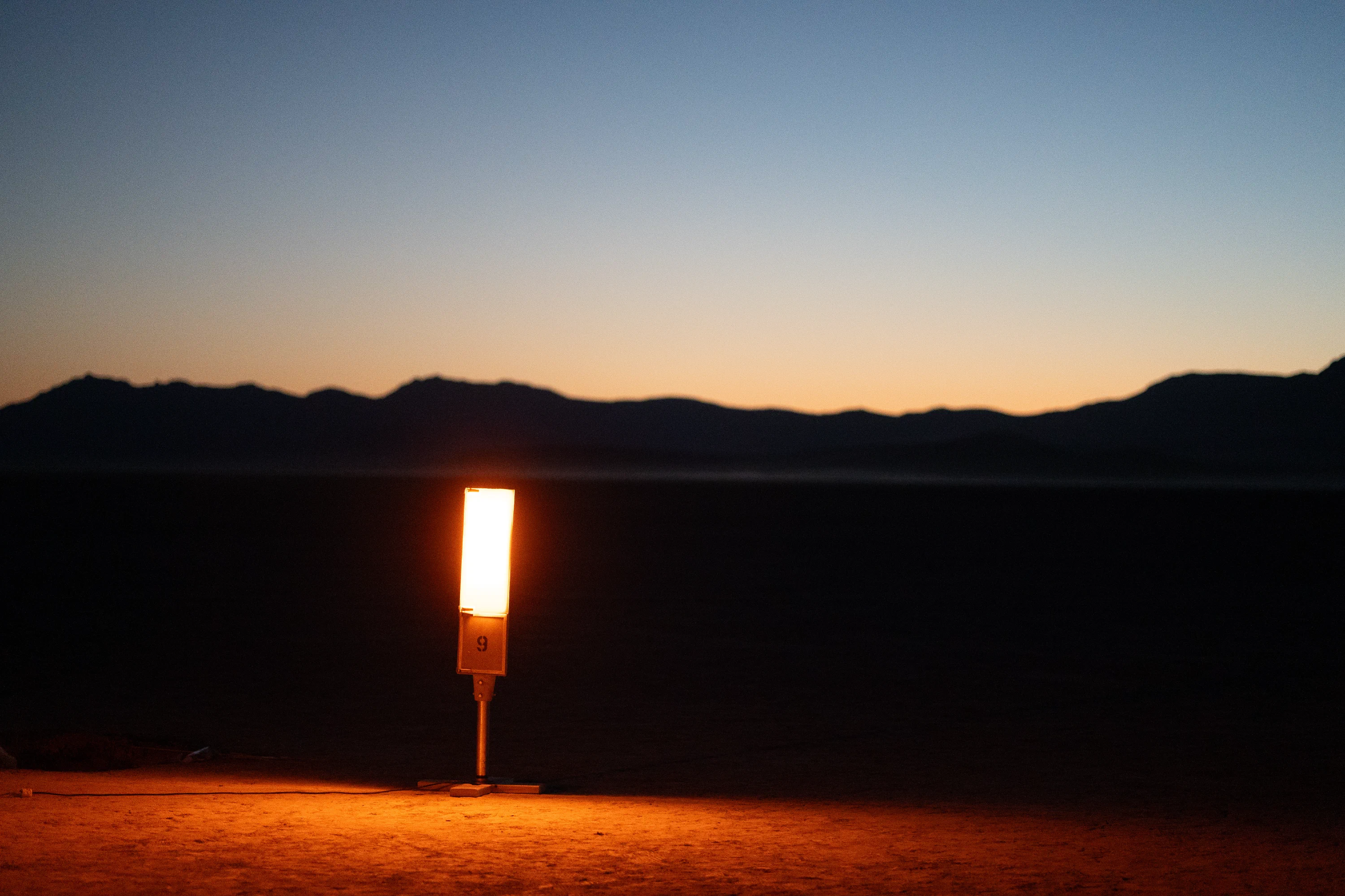 A streetlamp warming up on the playa at dusk